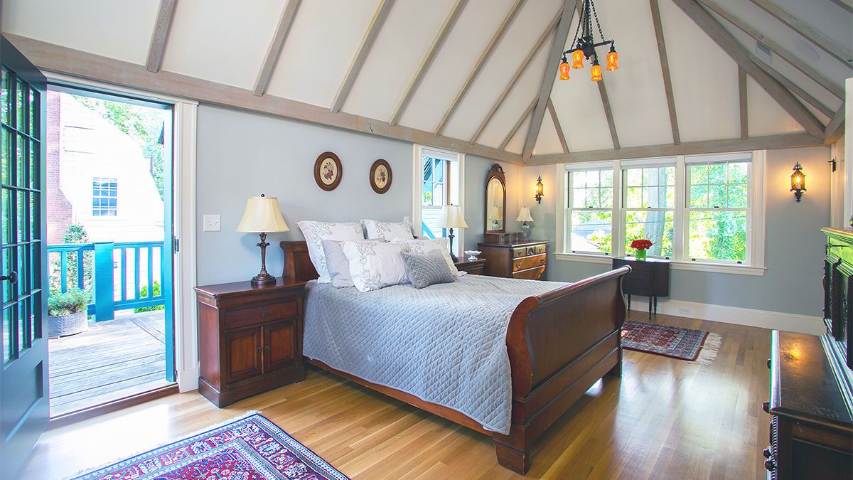 The master bedroom also has exposed decorative beams designed to look structural. To make this cathedral ceiling work, the roof assembly is unvented, with R-50 closed-cell spray-foam insulation between the rafters. The oak boards are pickled with a subtle gray finish for a little less contrast in the bright master bedroom.
