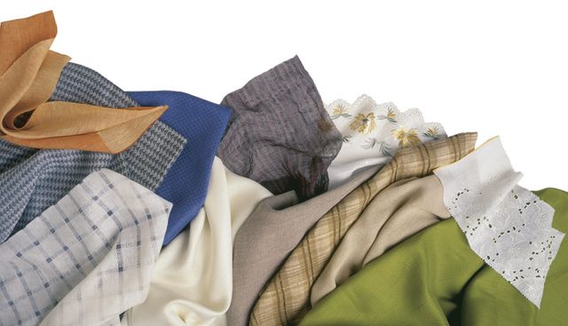 Fabric of different kinds for sewing clothes. Denim, costume, checkered,  blue red fabric for sewing clothes. Textile folded into a pile. Stock Photo